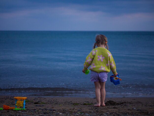 Une petite fille joue sur la plage le soir.