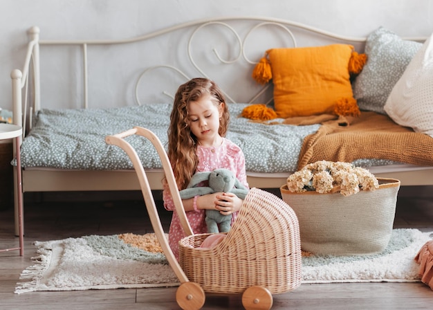 Une petite fille joue avec des poupées et une poussette dans une chambre d'enfants. Jeux pour enfants