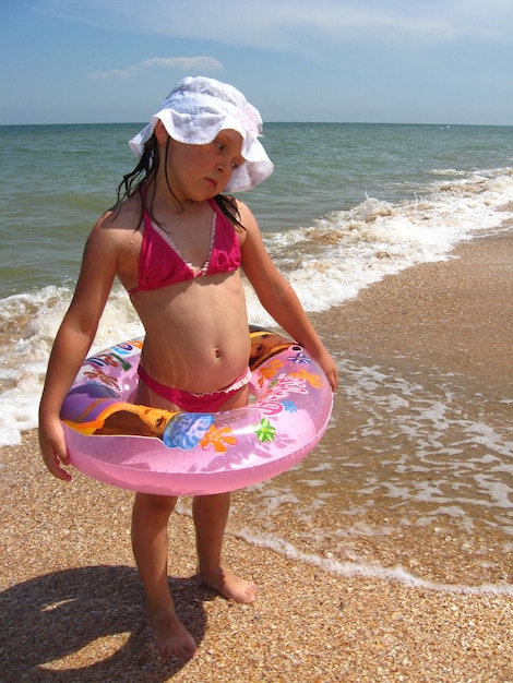 Une petite fille joue sur le sable de la mer.