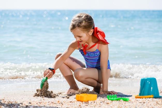 Petite fille jouer avec du sable à la plage