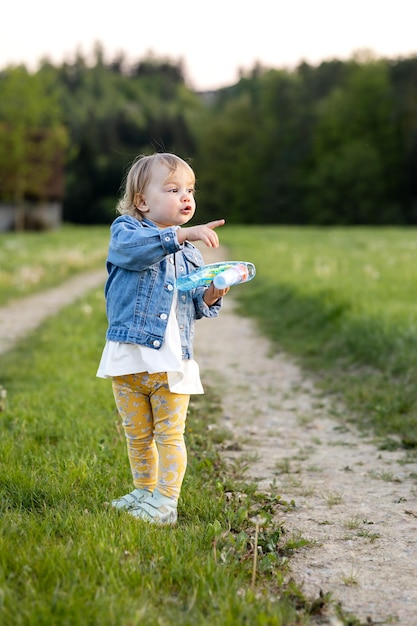 Petite fille avec un jouet dans ses mains sur un chemin dans un pré