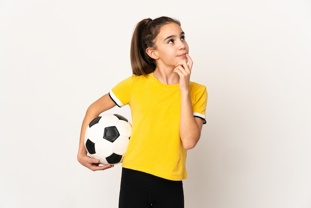 Petite fille de joueur de football isolée sur un mur blanc ayant des doutes tout en levant les yeux