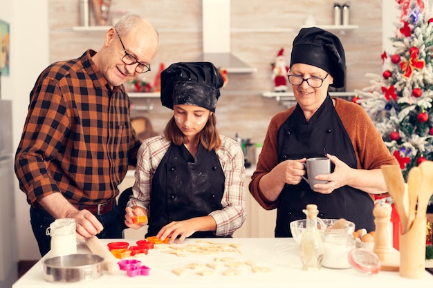 Petite-fille le jour de noël ayant de l'aide pour faire un dessert