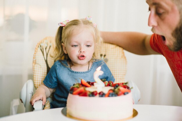 La petite fille le jour de son anniversaire accepte les félicitations et mange du gâteau