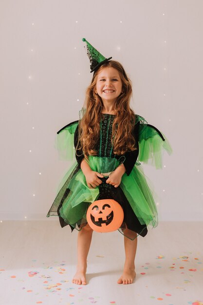 Petite fille joyeuse en costume de carnaval avec une lanterne citrouille Jack dans ses mains célèbre Halloween