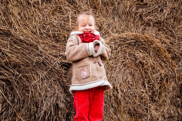 Une petite fille joyeuse à côté d'une botte de foin