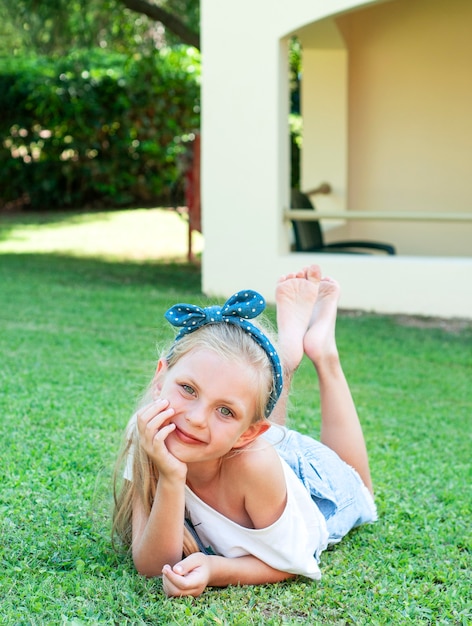 petite fille joyeuse dans une combinaison en jean, allongée sur une herbe verte