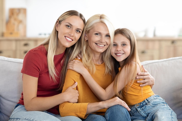 Photo petite fille joyeuse et jolie femme millénaire embrassant une femme âgée