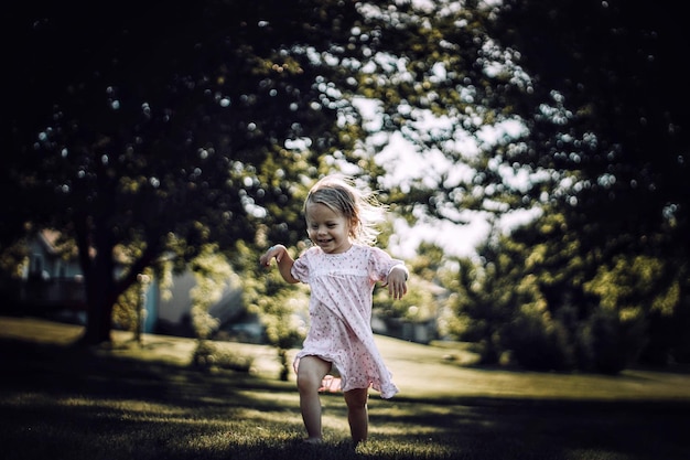 Une petite fille joyeuse qui marche sur un champ d'herbe.