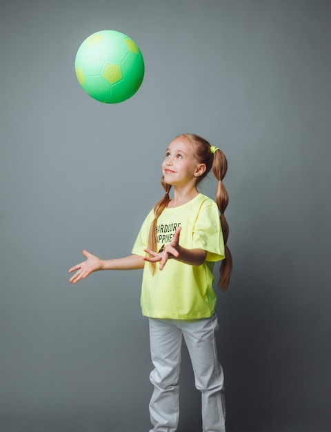 Photo une petite fille lance une balle isolée sur un fond gris un petit athlètesports pour enfants