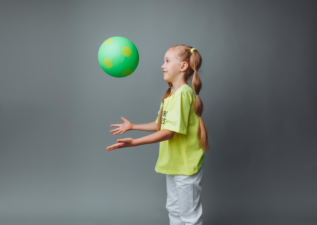 Photo une petite fille lance une balle isolée sur un fond gris un petit athlètesports pour enfants