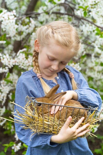 Petite fille avec un lapin dans le jardin, printemps