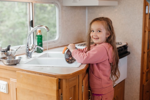 Petite fille lavant la vaisselle dans la cuisine d'une caravane