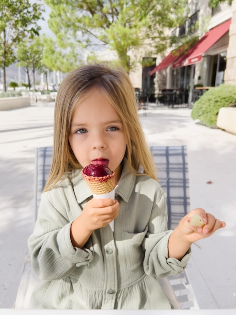 Petite fille lèche des sucettes glacées dans un cornet gaufré