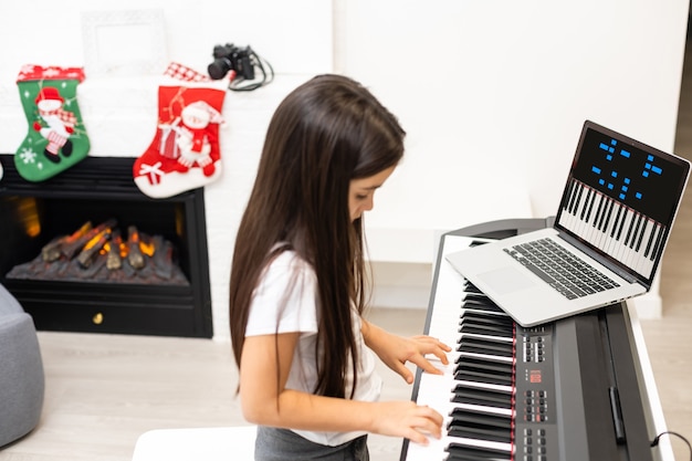 Une petite fille a une leçon en ligne avec un professeur sur le piano à Noël