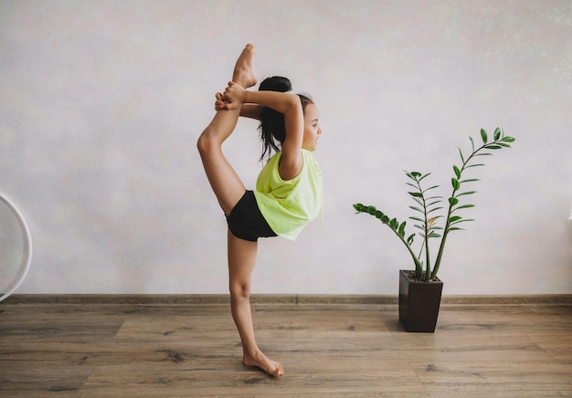 La petite fille en a levé la jambe Petite gymnaste s'entraîne à la maison enfant faisant des étirements