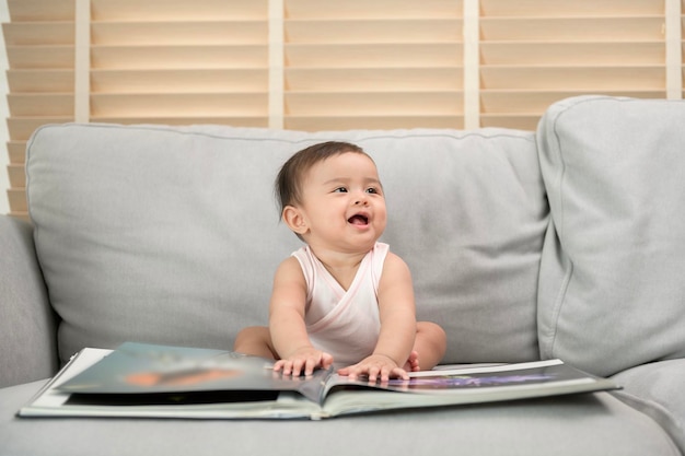 Petite fille lisant un livre assis sur un canapé à la maison