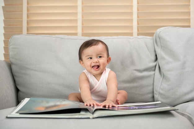 Petite fille lisant un livre assis sur un canapé à la maison