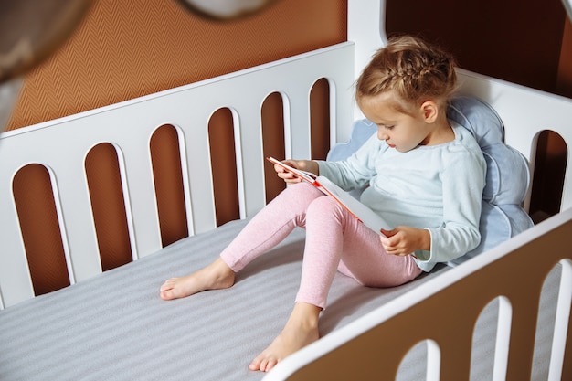 Petite fille lisant un livre dans la chambre