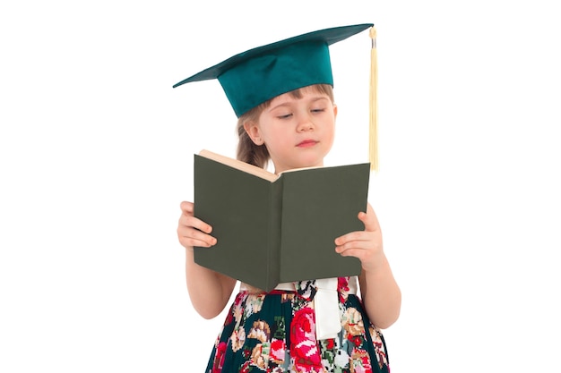 La petite fille lit attentivement le livre sur une surface blanche