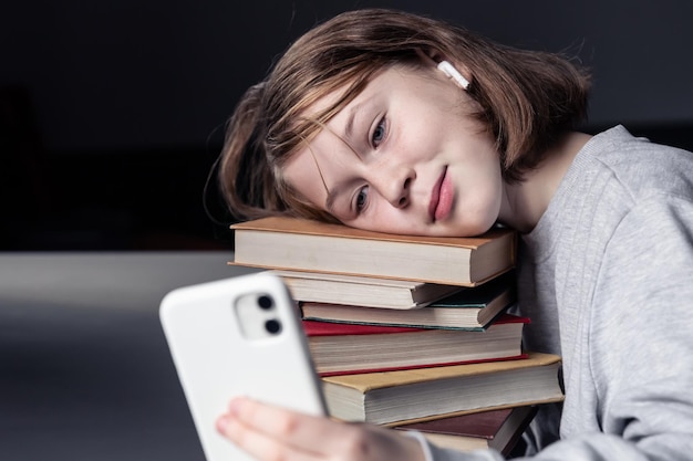 Petite fille avec des livres et un téléphone dans ses mains