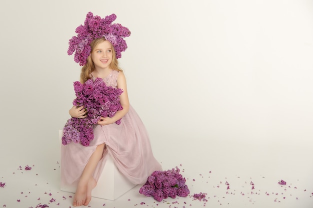 Petite fille lumineuse mignonne dans le studio avec lilas