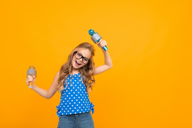 Une Petite Fille à Lunettes Avec Un Microphone Est Interviewée, La Photo Est Isolée Sur Un Mur Jaune