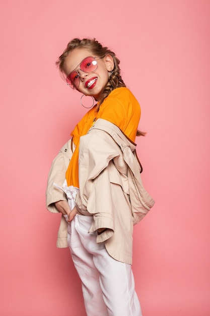 Petite fille à lunettes roses. Concept funtime élégant de style de mode à la mode. Portrait en pied vertical pleine grandeur de rire mignon doux adorable belle charmante fille isolée mur rose