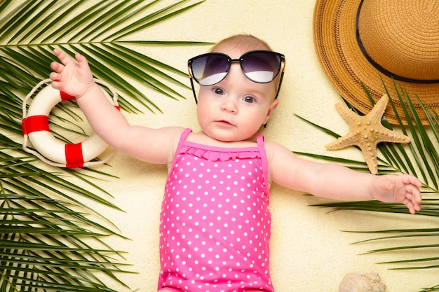 Petite fille à lunettes de soleil avec accessoires de plage. Vacances en mer avec bébé, concept d'été