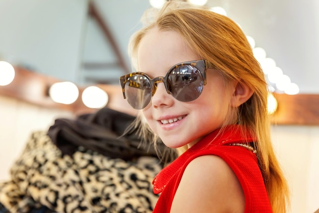 Petite fille à lunettes de soleil près du miroir