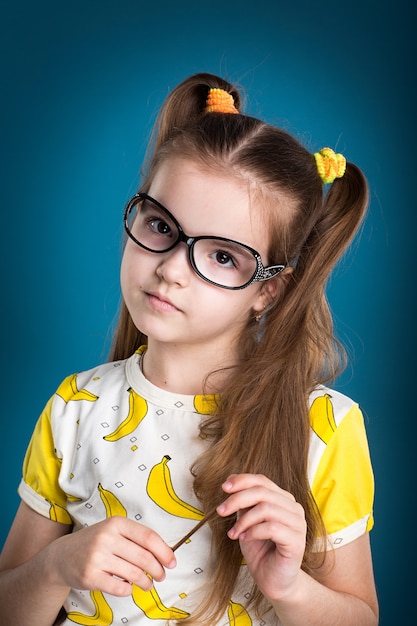 Petite fille à lunettes et T-shirt banane sur fond bleu