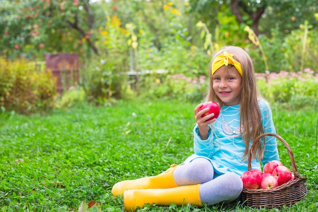 Petite fille magnifique avec un panier de pommes en automne