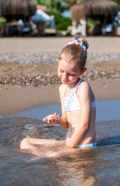 Petite fille en maillot de bain jouant sur la plage au bord de la mer