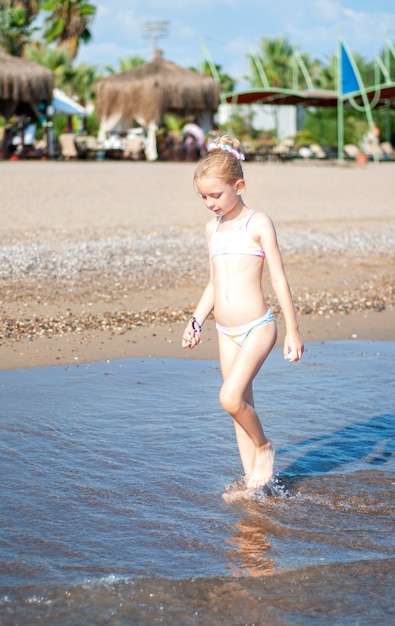 Petite fille en maillot de bain jouant sur la plage au bord de la mer