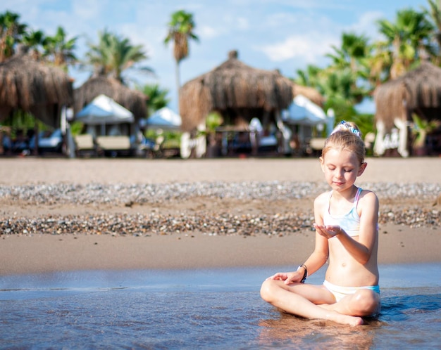 Petite fille en maillot de bain jouant sur la plage au bord de la mer