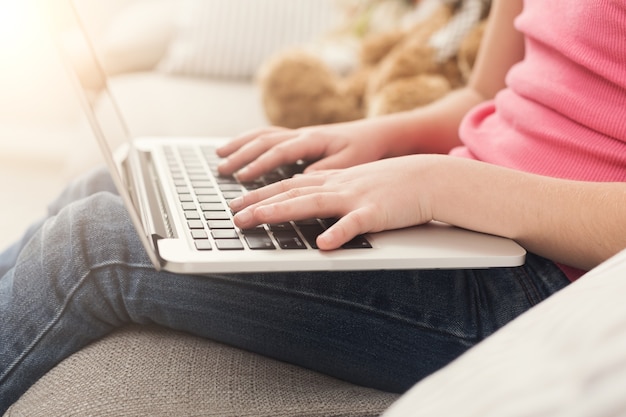 Petite fille mains sur clavier d'ordinateur portable se bouchent. Enfant méconnaissable faisant ses devoirs sur ordinateur. Concept moderne d'éducation, de communication et de technologie en ligne, espace de copie