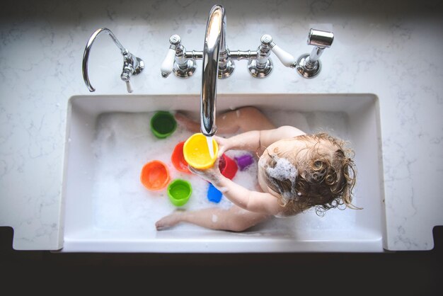 Une petite fille à la maison dans l'évier de la cuisine