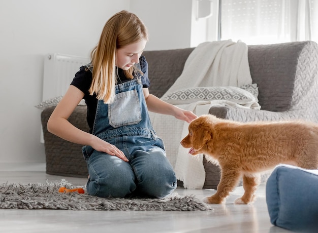 Une petite fille à la maison sur le sol avec un chiot de Nova Scotia Retriever un toller