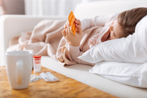 Petite fille malade couchée dans son lit et prendre des pilules à la maison