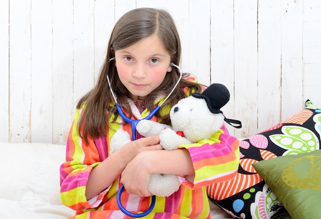 Une petite fille malade jouant avec sa peluche