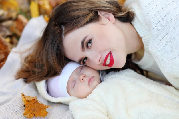 Petite fille une maman allongée sur un tapis et des feuilles d'automne