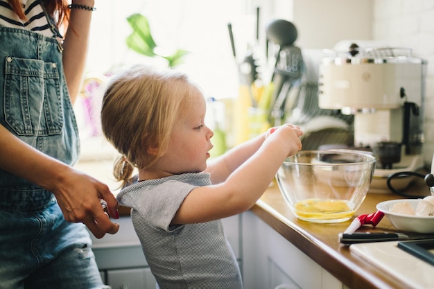 Petite fille avec maman dans la cuisine préparant le petit déjeuner