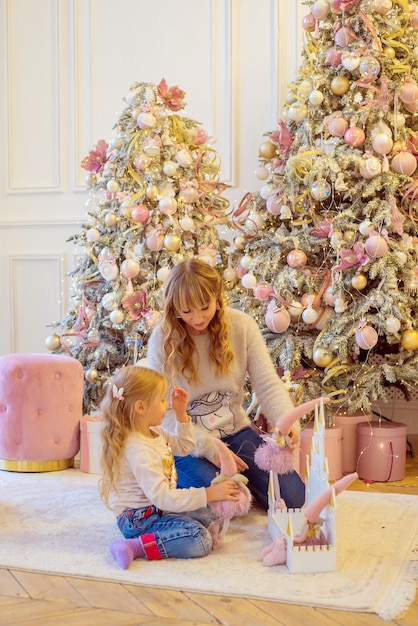 Petite fille avec maman jouant ensemble près de l'arbre de Noël à Noël