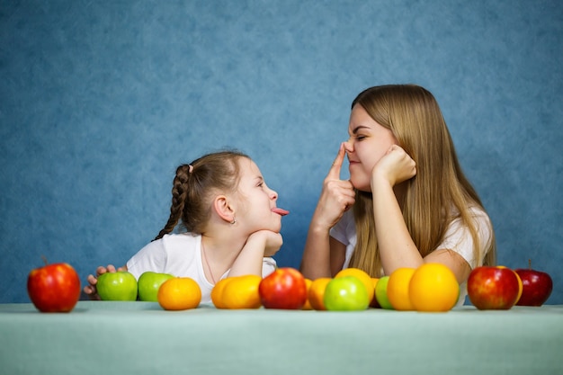 Petite fille et maman jouent avec des fruits et s'amusent. Ils portent des tee-shirts