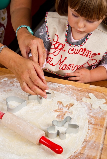 Petite fille avec maman préparant des biscuits de Noël coupant la pâtisserie avec un emporte-pièce