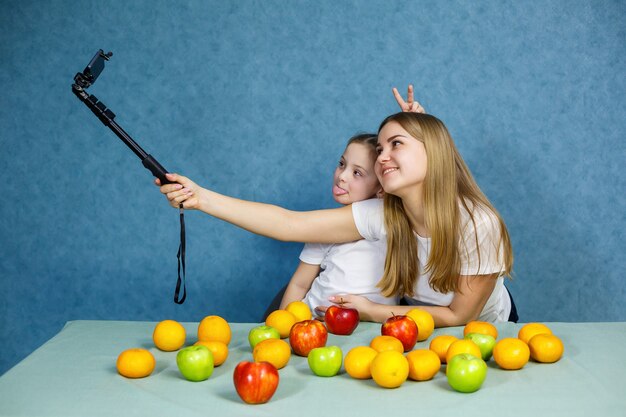 Petite fille avec maman en t-shirts blancs prend un selfie au téléphone et joue