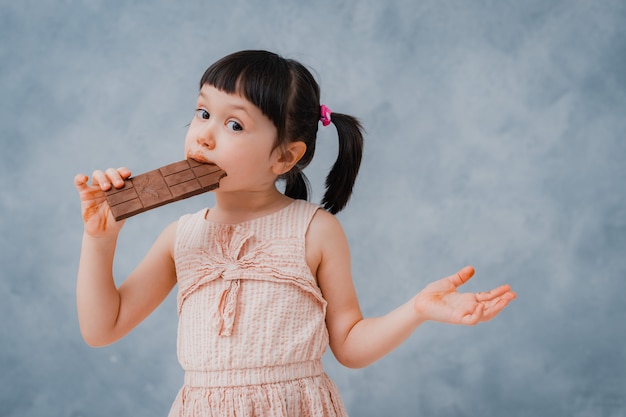 Petite fille mange du chocolat et lèche son doigt