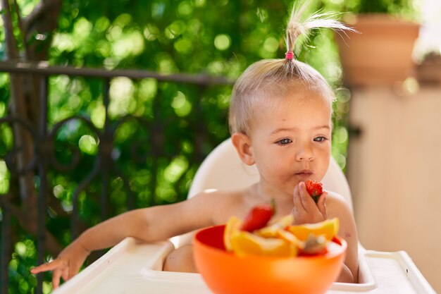 La petite fille mange des fraises perdues dans ses pensées