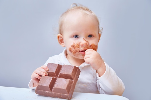 Une petite fille mange une grande barre de chocolat. Fermer. Copiez l'espace.