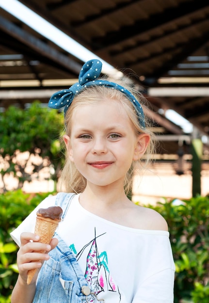 Petite fille mangeant de la crème glacée au chocolat à l'extérieur